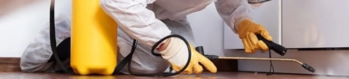Roach exterminator treating cracks and crevices along kitchen baseboards in Pittsburgh, PA